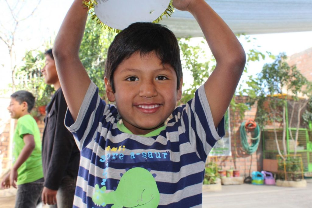Peruvian child smiling while holding gifts provided through HHK WMC’s Children of Jesus child sponsorship ministry